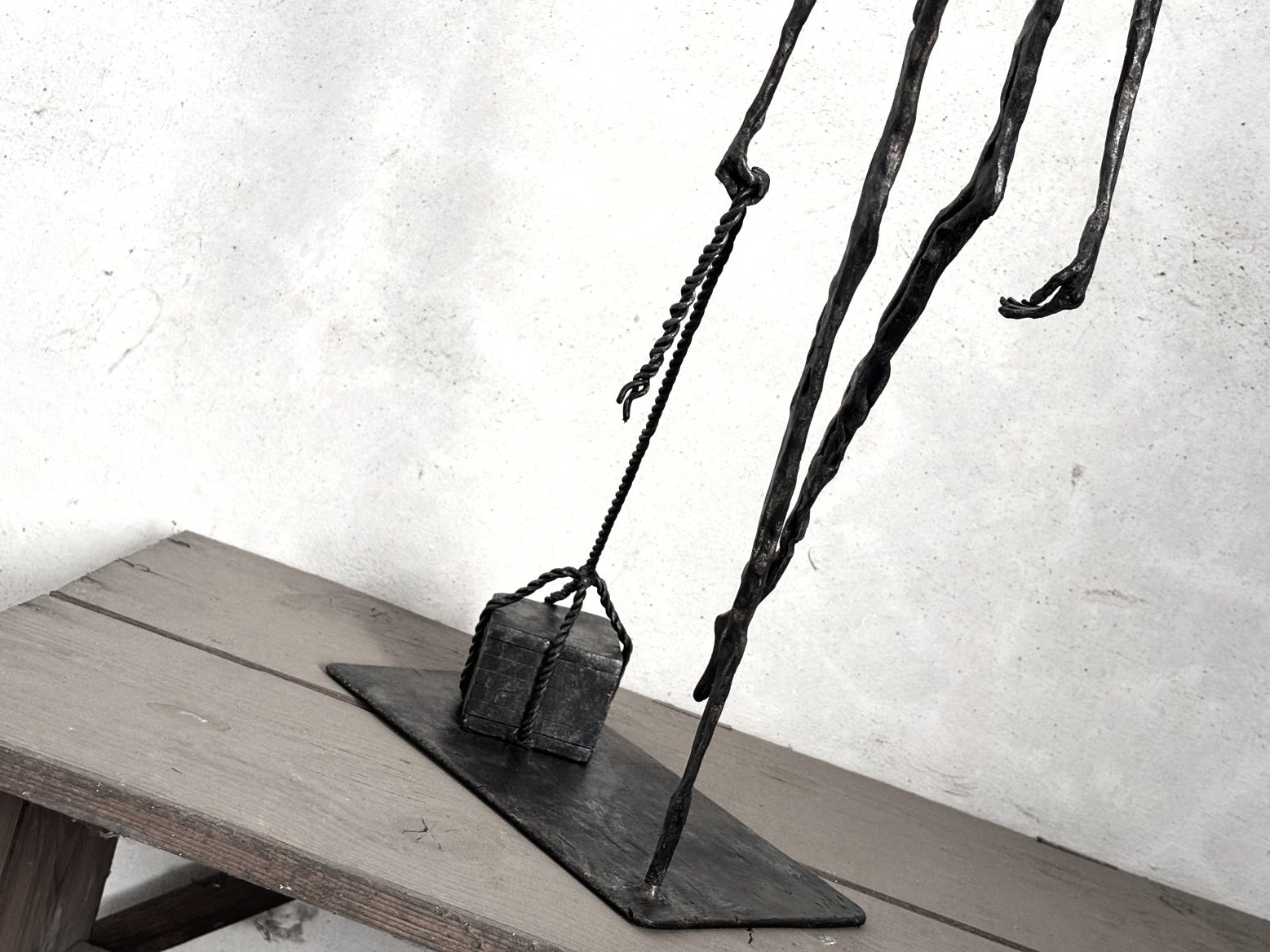 Photo depicting the hands of the forged sculpture Mea Culpa III. The right hand grips the rope with which the figure drags its burden of sins