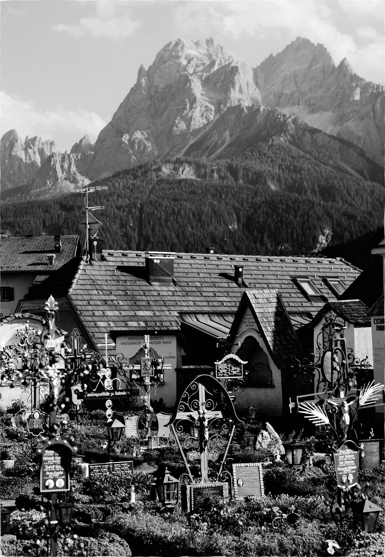 Forged crosses located in northern Italy, with a house and a mountain in the background